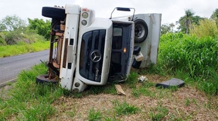 Caminhão basculante com carga de areia tomba em vicinal