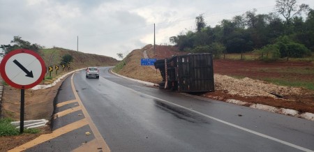 Após bater em canaleta, caminhão carregado com pó de serra tomba em alça de acesso da SP-294